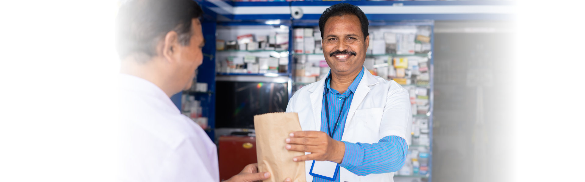 Smiling pharmacist giving medicine cover to customer at pharmacy shop